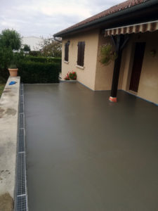 Construction de terrasse en béton lissé avec caniveau en bas de pente pour récupération de l'eau de pluie